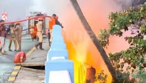 Firefighting operations at a burning scrap shop near Pullepady Bridge in Ernakulam, Kochi, with smoke rising high.